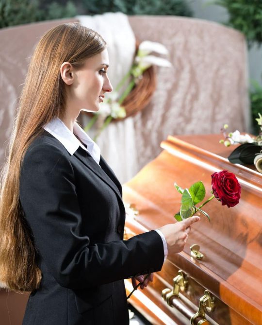 Woman standing next to a coffin at a burial service